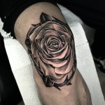Tatouage de rose réaliste en noir sur le genou