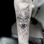 Loup tatoué sur l'avant bras en style graphique et en noir